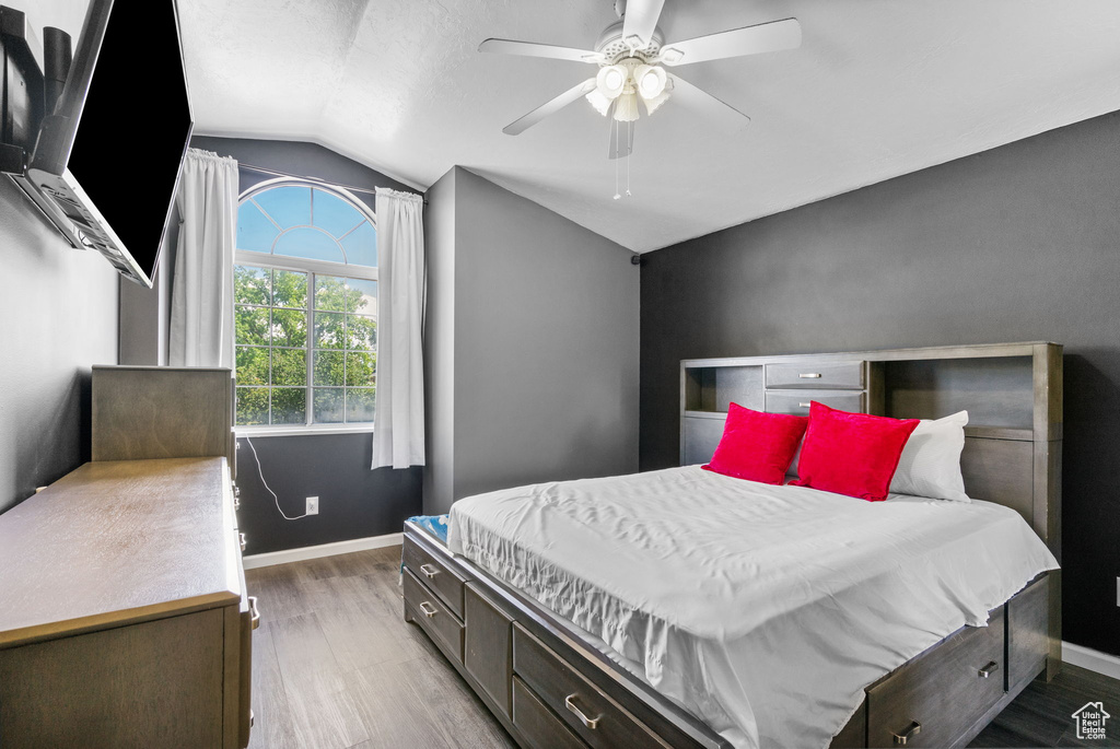 Bedroom featuring vaulted ceiling, wood finished floors, baseboards, and a ceiling fan