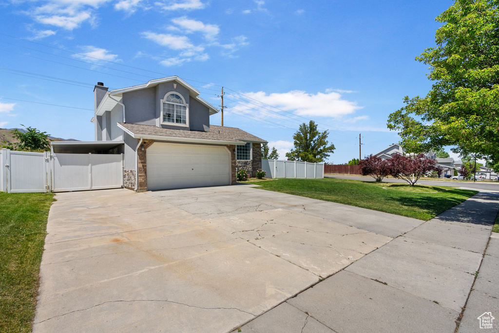 View of front of property with concrete driveway, a gate, a garage, stucco siding, and stone siding