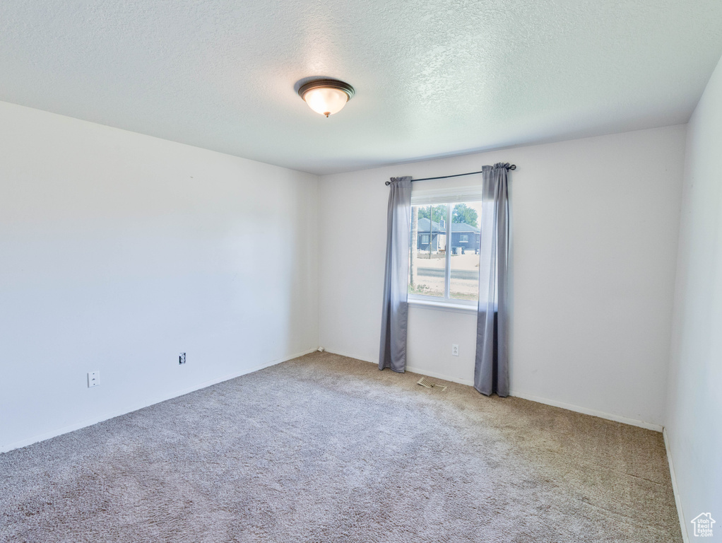 Carpeted empty room with a textured ceiling