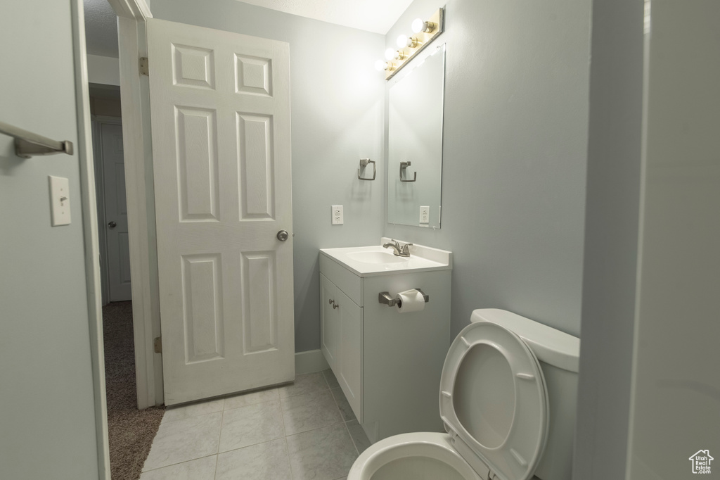 Bathroom with vanity, toilet, tile patterned floors, and baseboards