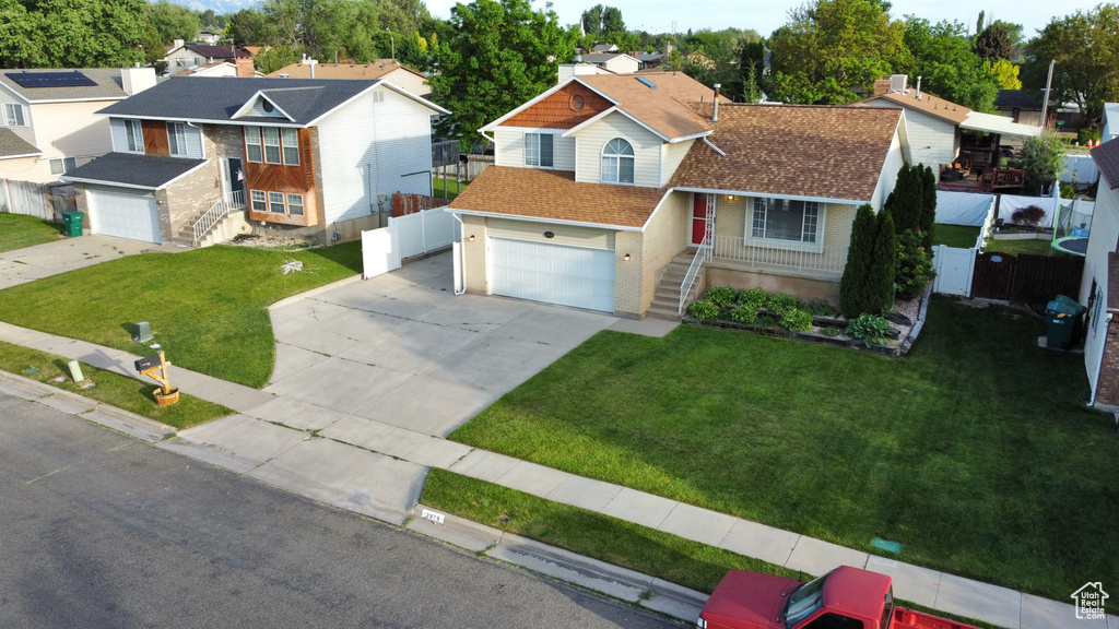 View of front of home with concrete driveway, a garage, a residential view, and a shingled roof