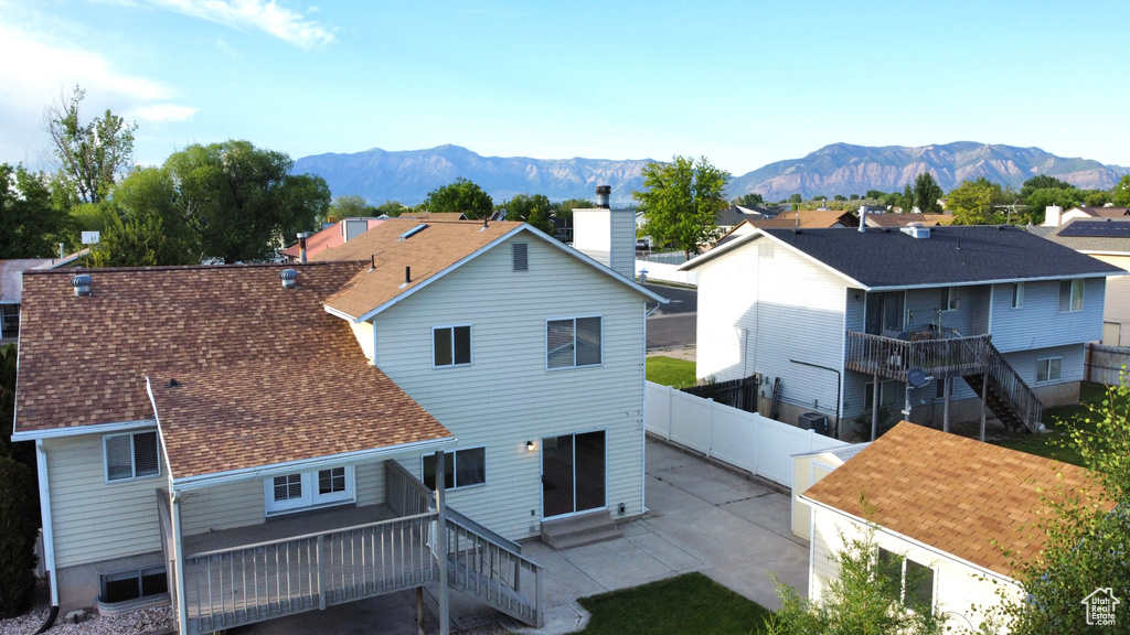 Rear view of property featuring a fenced backyard, a patio, stairway, roof with shingles, and a residential view