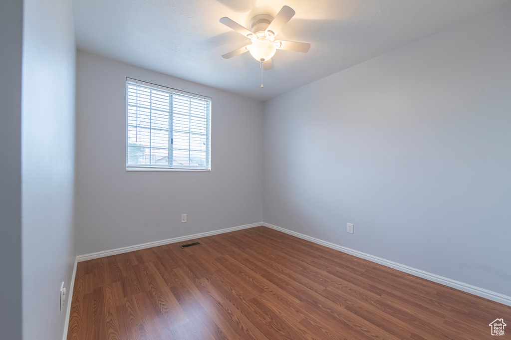 Spare room with wood finished floors, ceiling fan, and baseboards