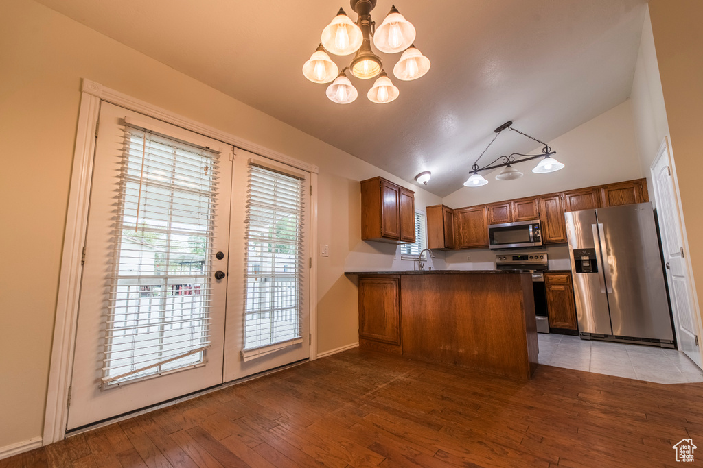 Kitchen with stainless steel appliances, dark countertops, vaulted ceiling, french doors, and a chandelier