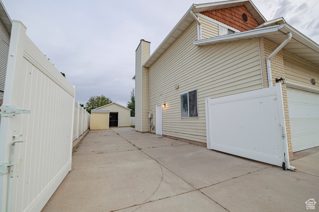 View of home's exterior featuring a garage, concrete driveway, and a chimney