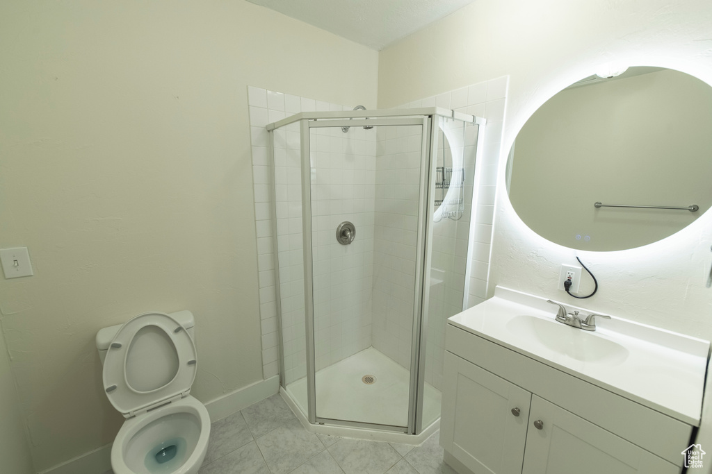 Bathroom with a shower stall, vanity, toilet, and baseboards