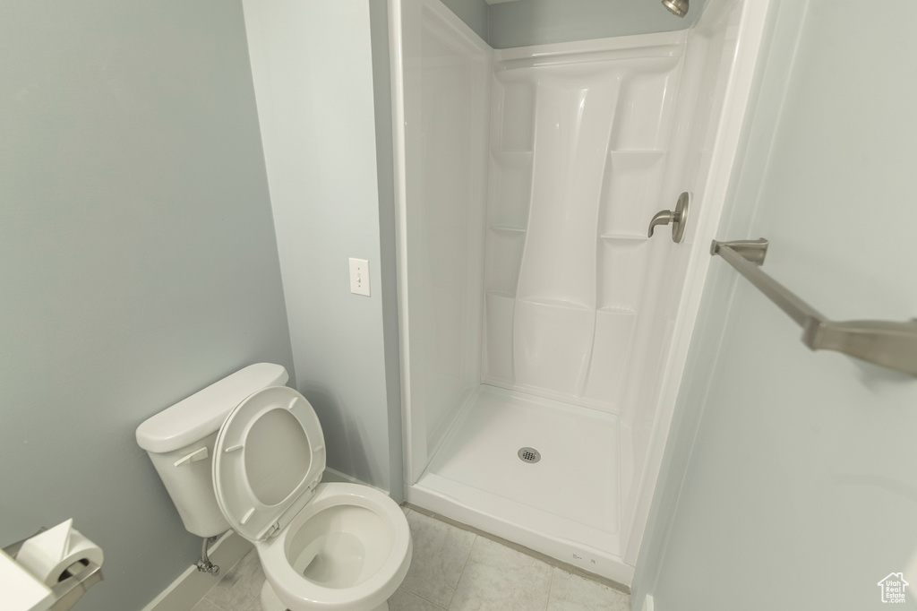 Full bath with a shower stall, toilet, and tile patterned floors