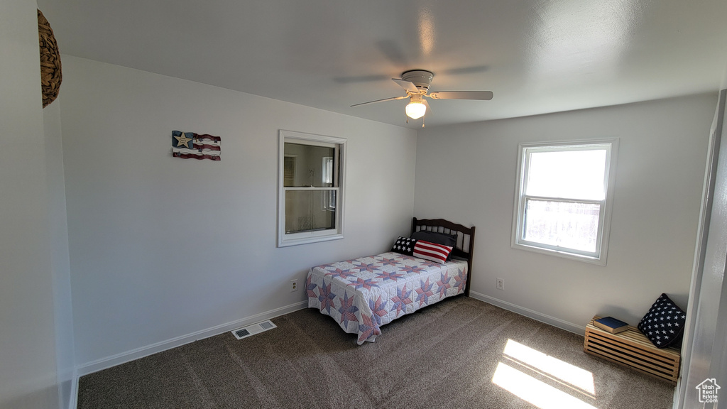 Bedroom with dark colored carpet, baseboards, and a ceiling fan