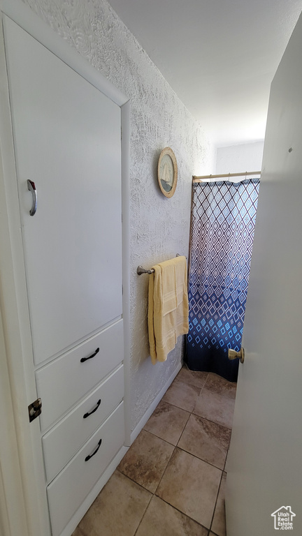 Bathroom with a textured wall and tile patterned flooring