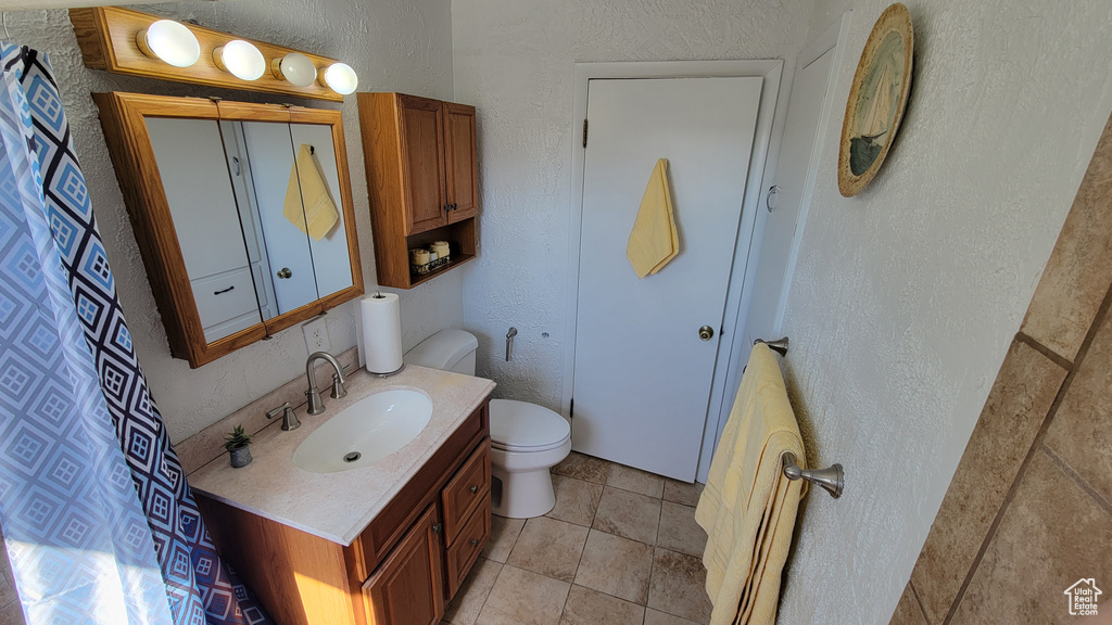 Bathroom with vanity, toilet, and a textured wall