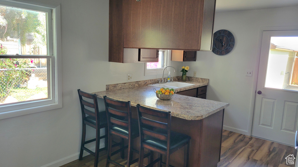 Kitchen with a sink, light countertops, dark wood-style flooring, baseboards, and a peninsula