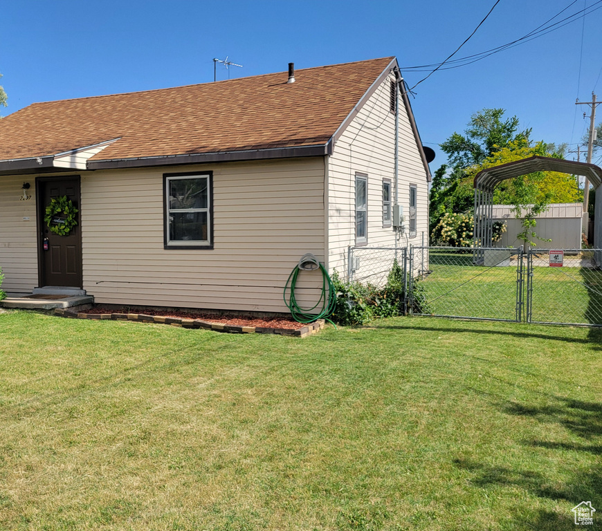 View of front of home with roof with shingles, a detached carport, and a gate