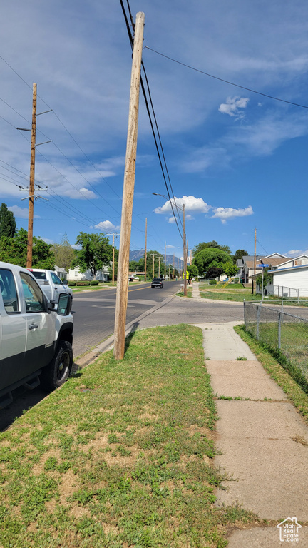View of asphalt street featuring sidewalks and street lighting