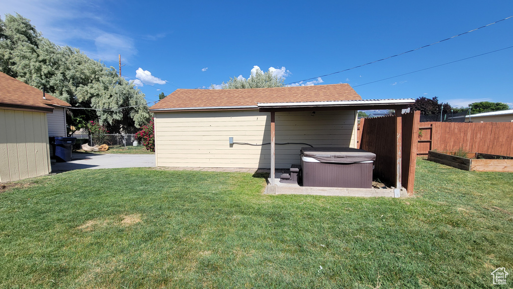 Rear view of property with a hot tub and a patio area