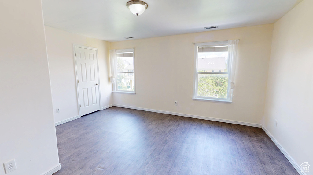 Empty room with healthy amount of natural light, wood finished floors, and baseboards