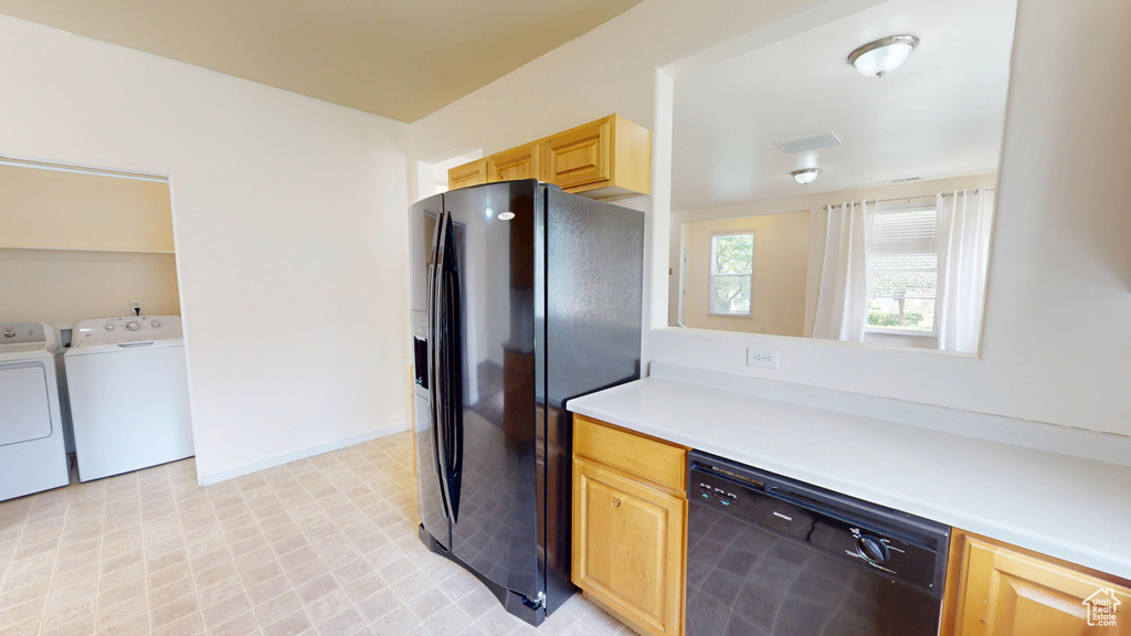 Kitchen featuring black appliances, separate washer and dryer, light brown cabinetry, light countertops, and light flooring