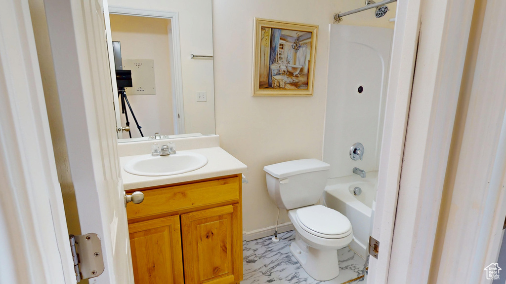 Bathroom featuring toilet, vanity, shower / bath combination, and baseboards