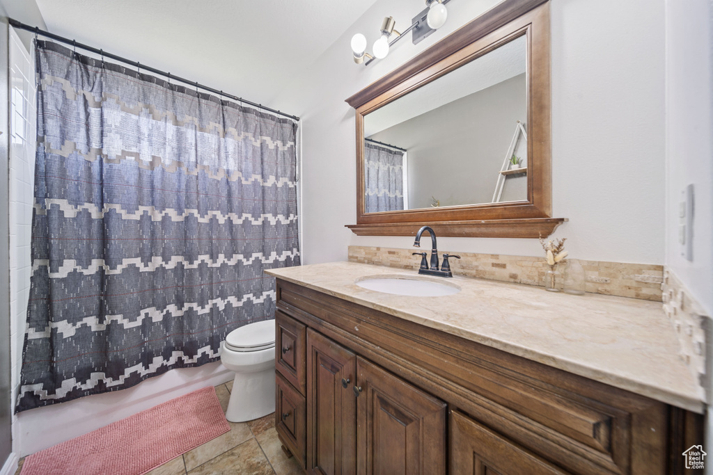 Bathroom featuring vanity, toilet, and curtained shower