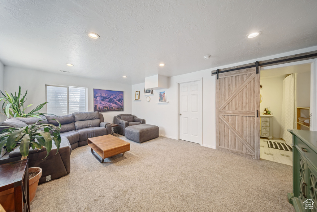 Living area with light carpet, a barn door, recessed lighting, and a textured ceiling