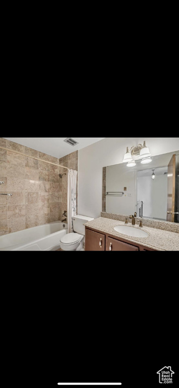 Bathroom featuring vanity, toilet, and shower / bath combination with curtain