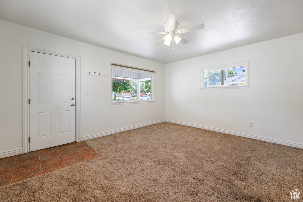 Carpeted spare room with a ceiling fan and baseboards