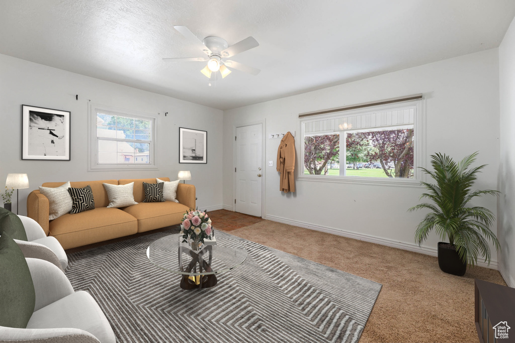 Living area with carpet flooring, a ceiling fan, and baseboards
