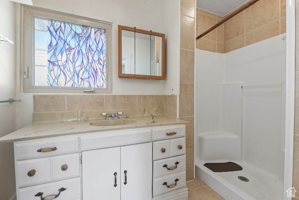 Bathroom with a shower, vanity, and plenty of natural light