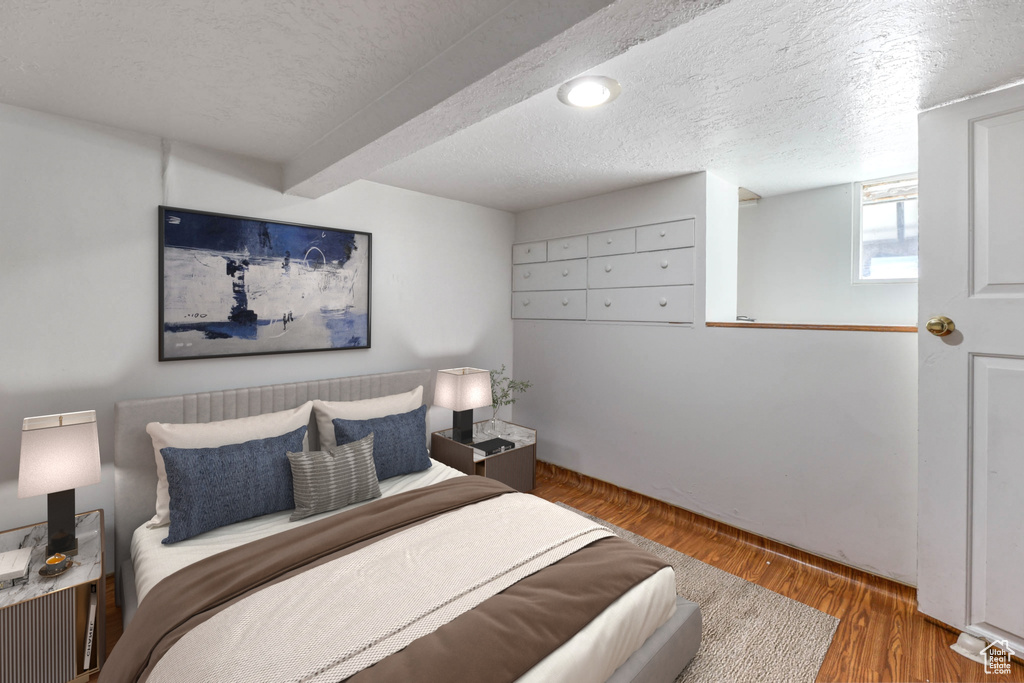Bedroom featuring wood finished floors, a textured ceiling, and beamed ceiling
