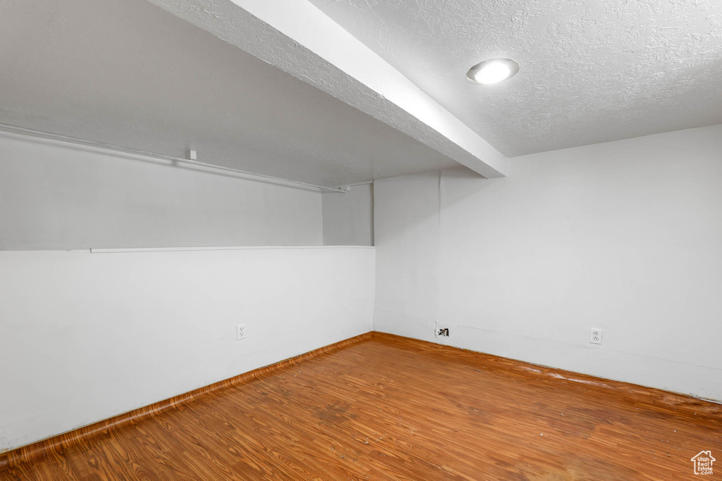 Finished basement featuring a textured ceiling, wood finished floors, recessed lighting, and baseboards