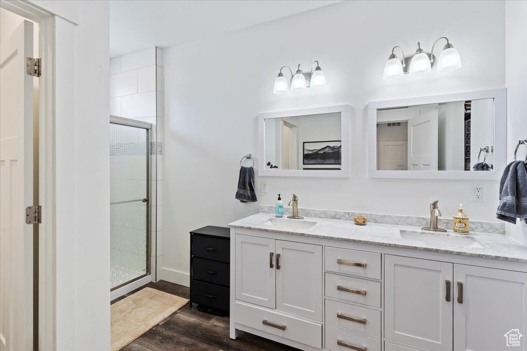 Bathroom with a stall shower, double vanity, and wood finished floors