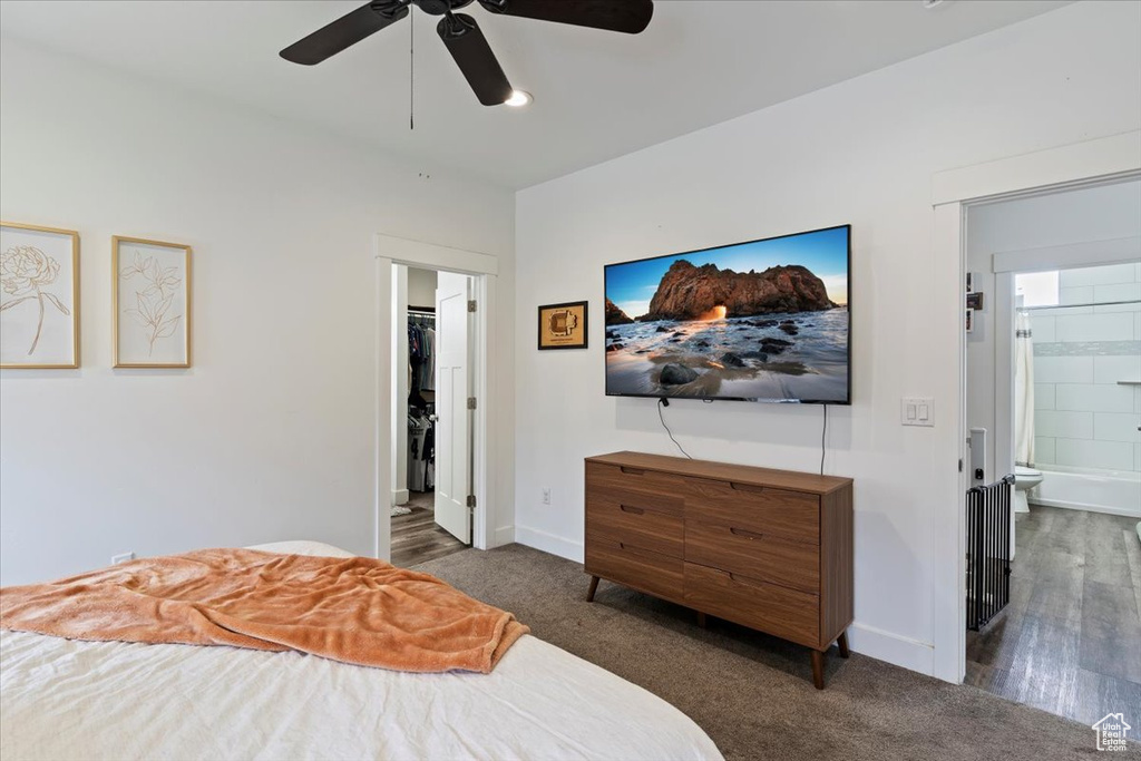 Carpeted bedroom with connected bathroom, baseboards, and ceiling fan