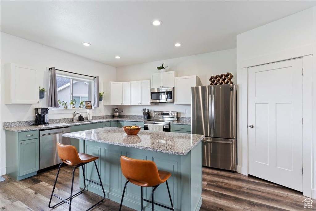 Kitchen featuring appliances with stainless steel finishes, a kitchen bar, a kitchen island, white cabinets, and recessed lighting
