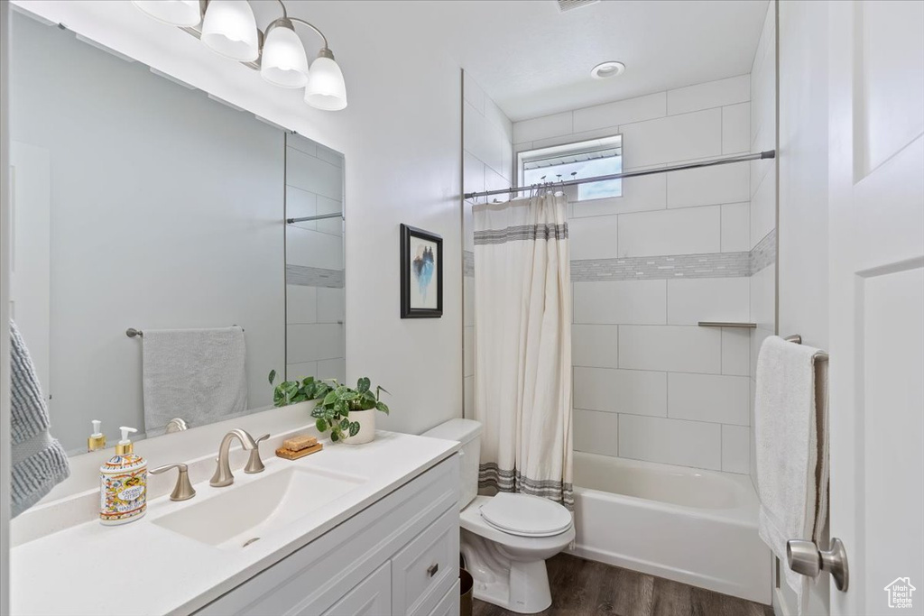 Full bathroom with vanity, toilet, wood finished floors, and shower / tub combo with curtain