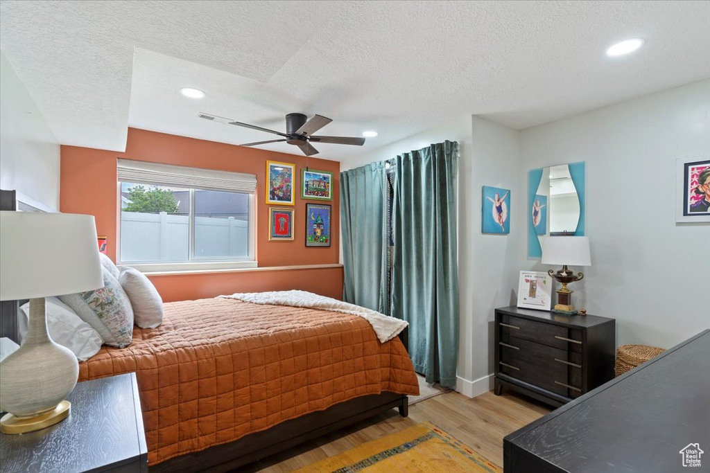 Bedroom with light wood-style floors, recessed lighting, ceiling fan, a textured ceiling, and baseboards