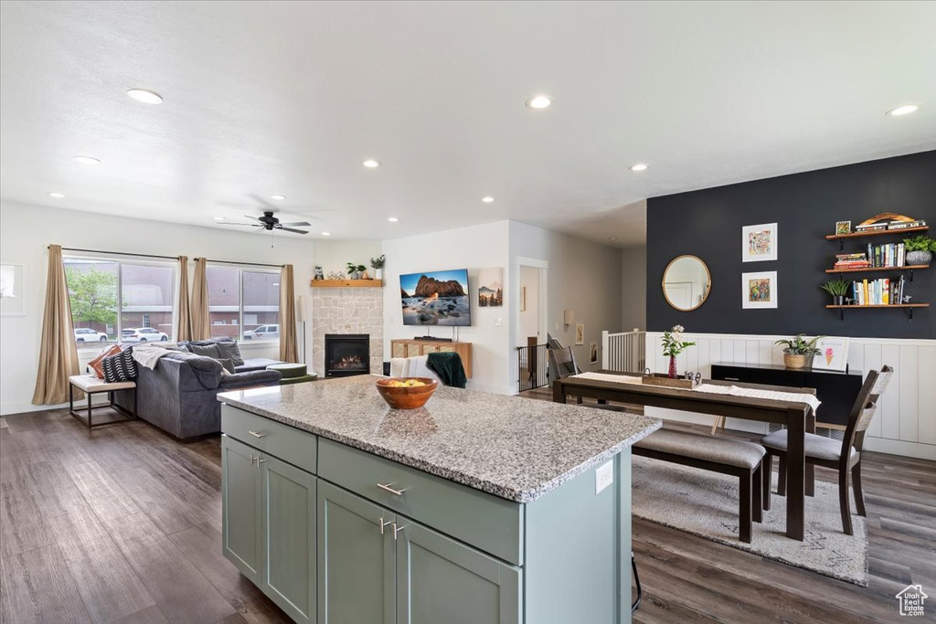 Kitchen with recessed lighting, a center island, dark wood-style floors, a ceiling fan, and a tiled fireplace