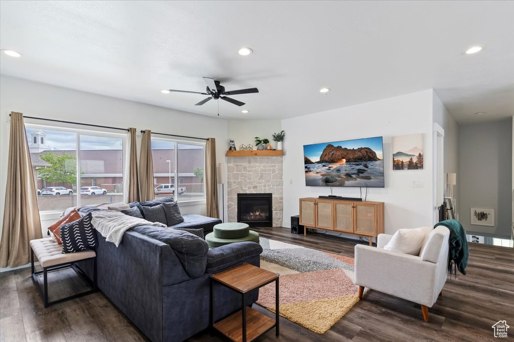 Living room featuring dark wood-style floors, recessed lighting, ceiling fan, and a stone fireplace