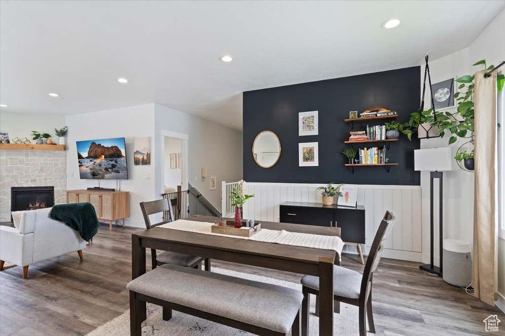 Dining area featuring wood finished floors, recessed lighting, a wainscoted wall, and a fireplace