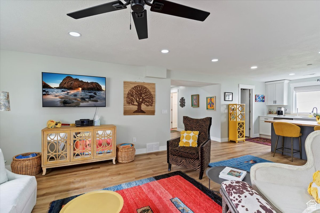 Living room with a ceiling fan, light wood finished floors, recessed lighting, and baseboards