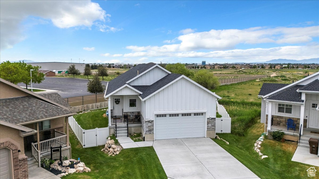 View of front facade with board and batten siding, a gate, concrete driveway, a garage, and a shingled roof