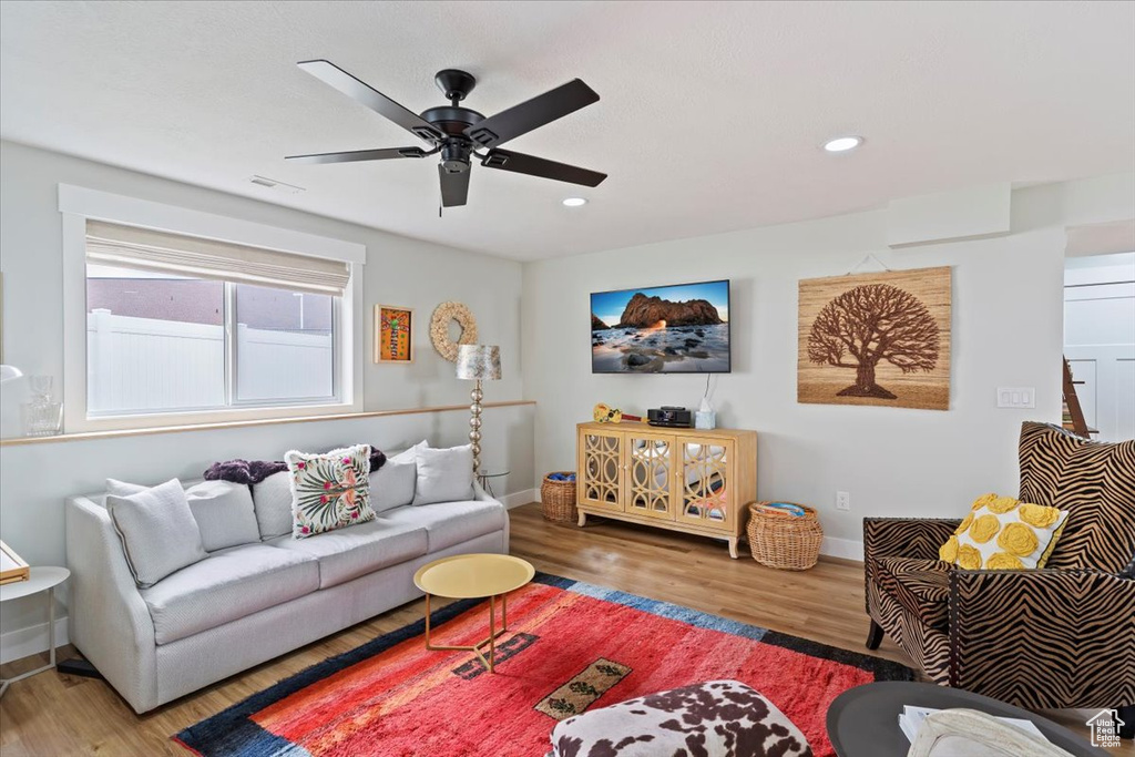 Living room featuring wood finished floors, baseboards, ceiling fan, and recessed lighting
