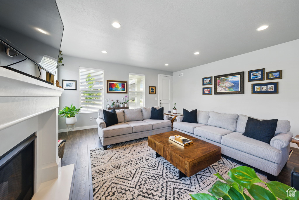 Living room with a fireplace, recessed lighting, hardwood / wood-style flooring, and baseboards