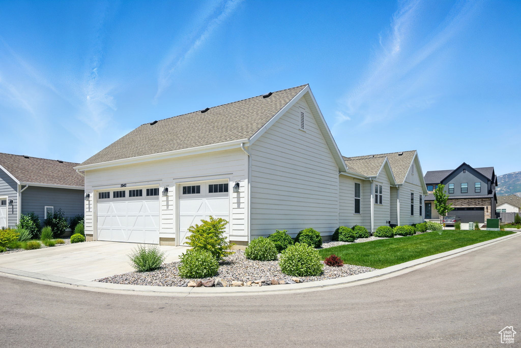 View of property exterior with a garage, concrete driveway, and roof with shingles
