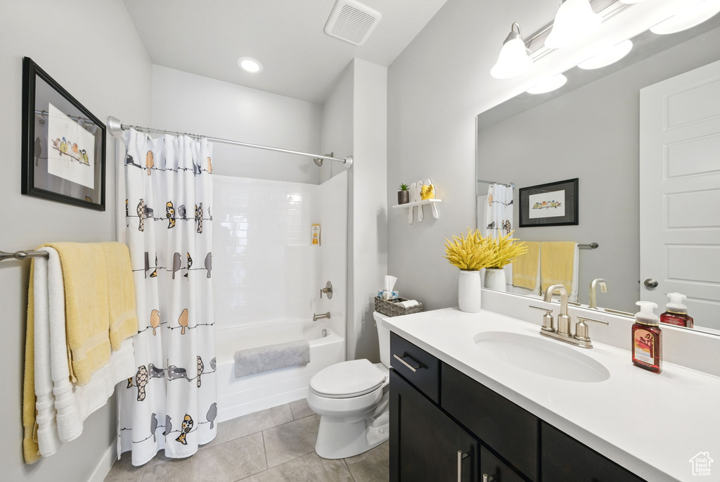 Bathroom featuring vanity, shower / bath combination with curtain, toilet, and tile patterned floors