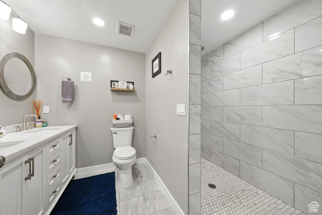 Full bath with double vanity, walk in shower, toilet, recessed lighting, and baseboards