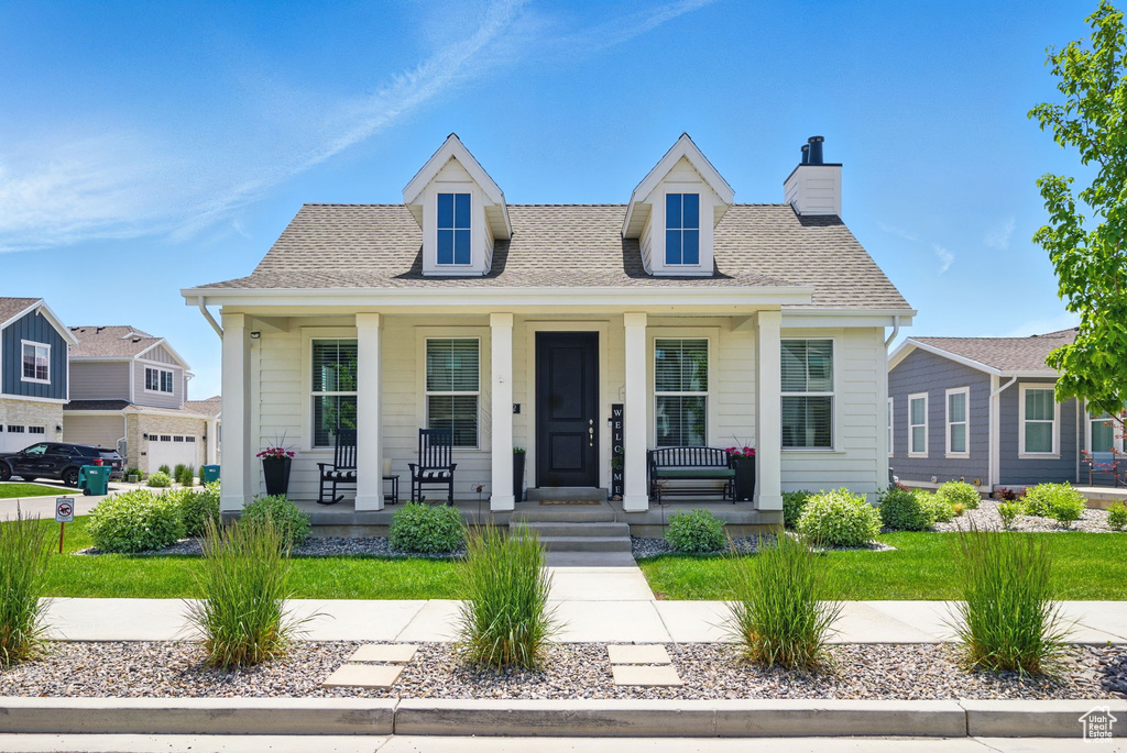 View of front of home featuring a porch, a chimney, and a shingled roof