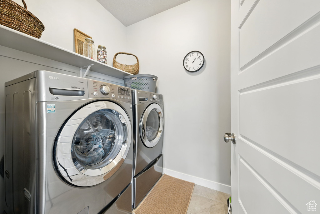 Laundry room with independent washer and dryer, baseboards, and light tile patterned flooring