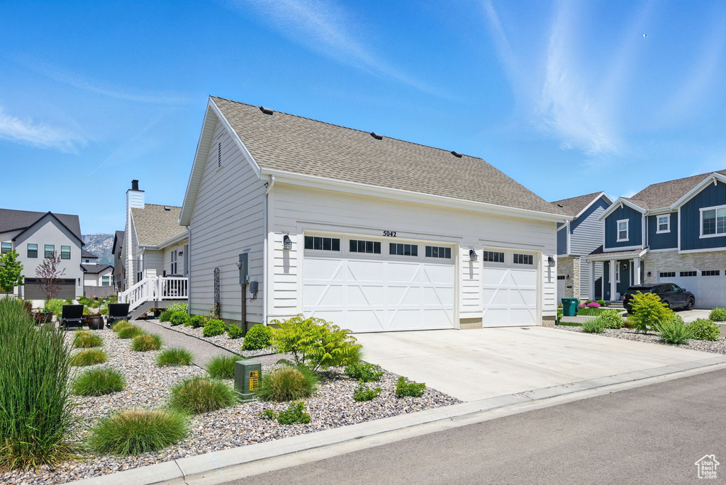 View of front facade featuring a residential view, concrete driveway, and an attached garage