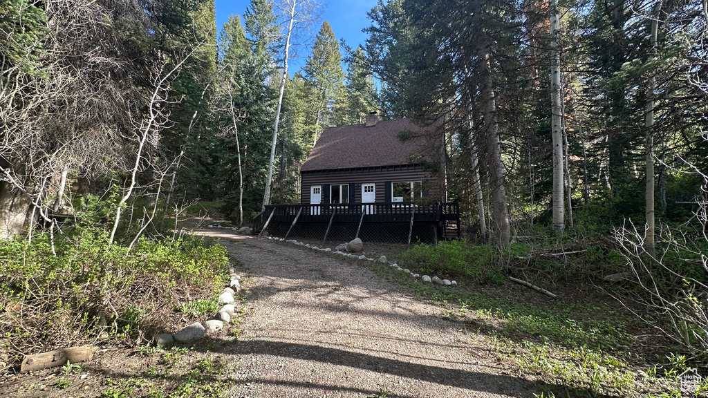 Chalet / cabin with a wooden deck, a chimney, and dirt driveway
