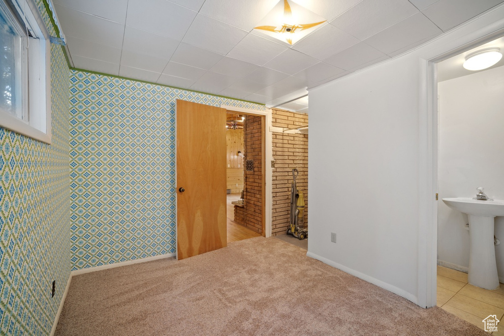 Unfurnished bedroom featuring carpet floors, wallpapered walls, baseboards, a sink, and connected bathroom