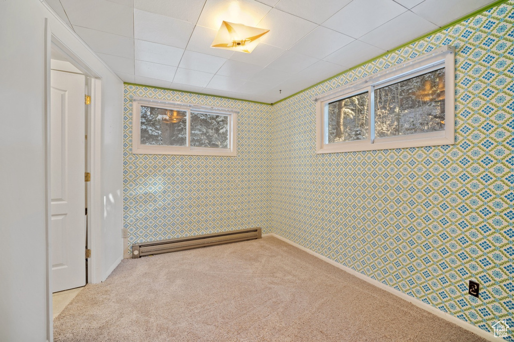 Spare room with a baseboard heating unit, carpet, and wallpapered walls